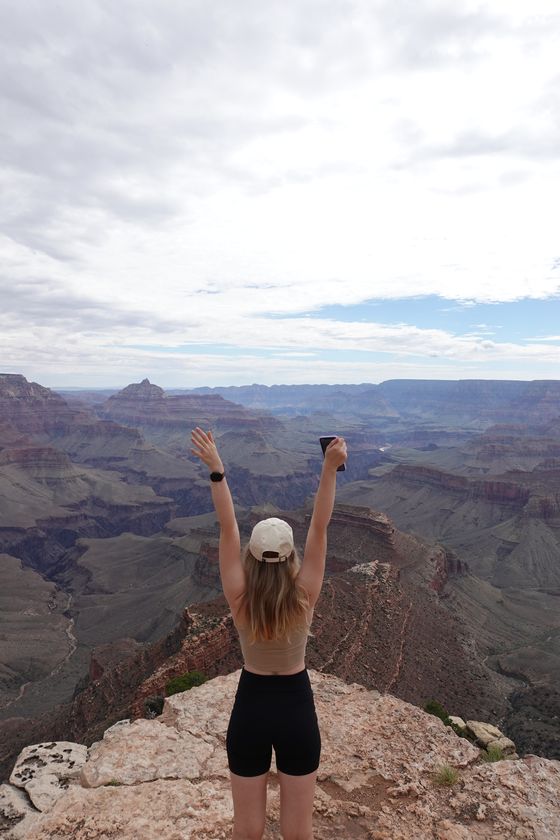 Diana from behind with arms raised at the Grand Canyon