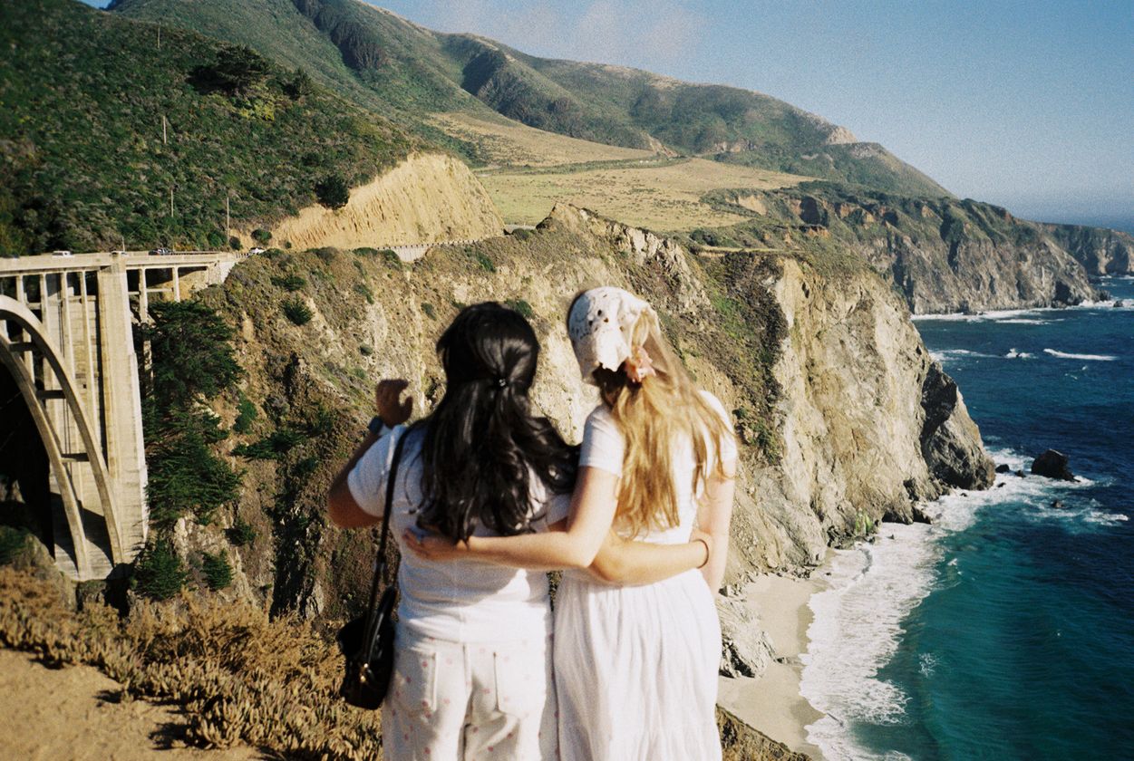 Two friends hugging in front of Bixby Bridge on the California coast