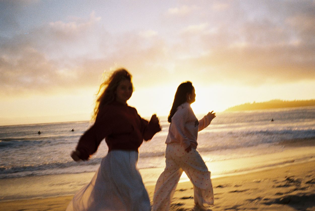 Two friends walking on a beach at sunset, shot on film
